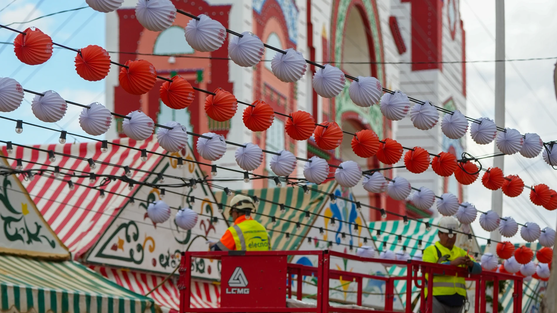 Trabajadores colocan los farolillos en el Real de la feria. A 05 de mayo de 2025, en Sevilla (Andalucía, España). Feria de Abril en Sevilla 2025: Más de 250.000 bombillas se encenderán esta 'Noche del Pescaíto' en el Real. La Feria de Abril de Sevilla, que este año tiene lugar en mayo, arranca esta medianoche con el alumbrado de las 25.000 bombillas LED de la portada, que este año representa el Pabellón de Chile de la Exposición Iberoamericana de 1929, y las 254.000 bombillas repartidas a lo ...