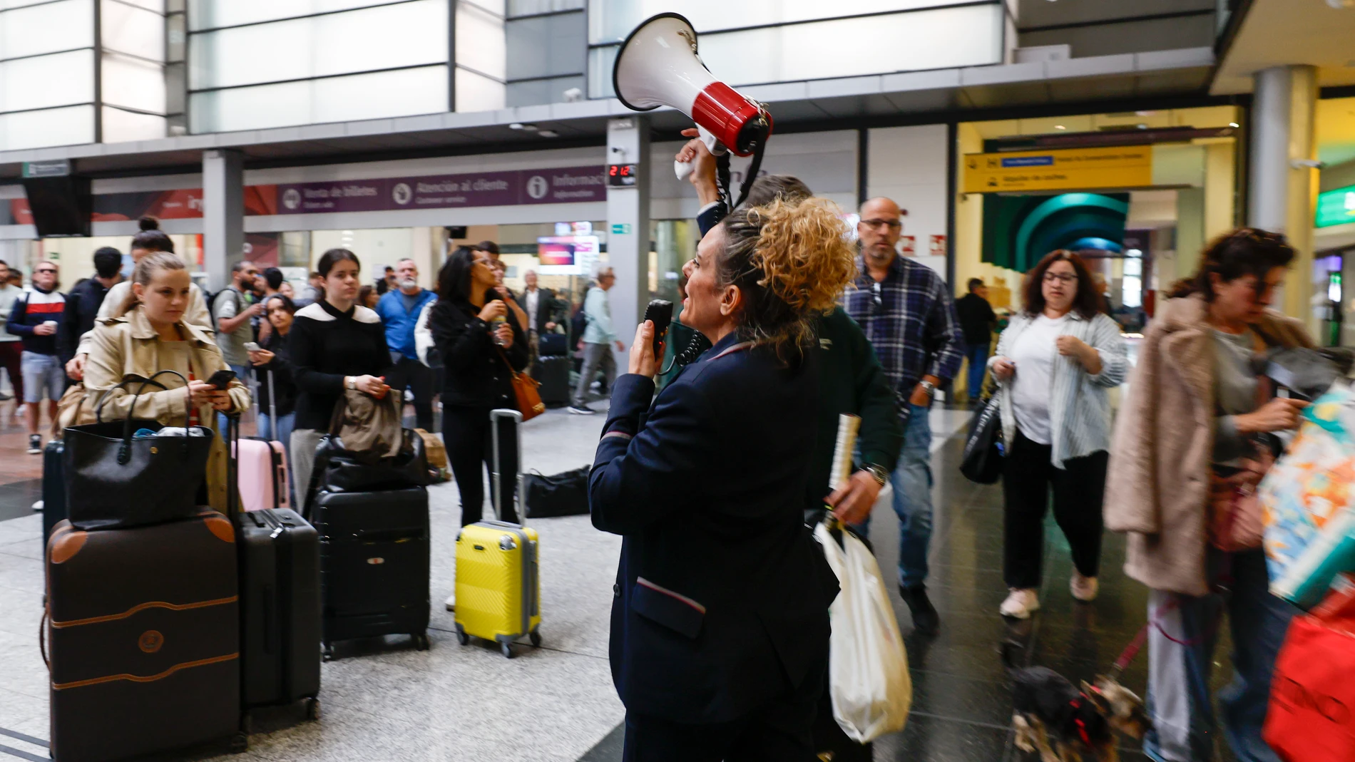 MÁLAGA, 05/05/2025.- Una empleada de Renfe informa a los viajeros aguardan en la Estación María Zambrano de Málaga la reanudación del servicio de alta velocidad este lunes tras el robo de cable en cuatro puntos de la provincia de Toledo que ha dejado miles de pasajeros afectados. EFE/Jorge Zapata
