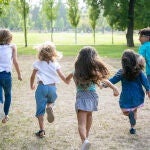 Grupo de niños corriendo juntos sobre la hierba, con carrera en el parque