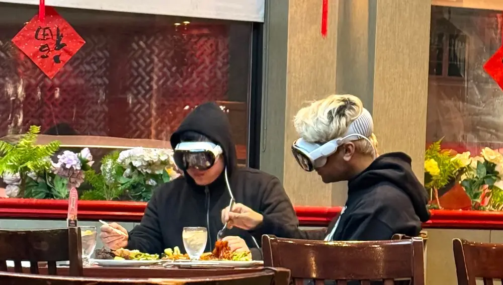 Dos jóvenes usando unas Apple Vision Pro mientras comen en un restaurante asiático