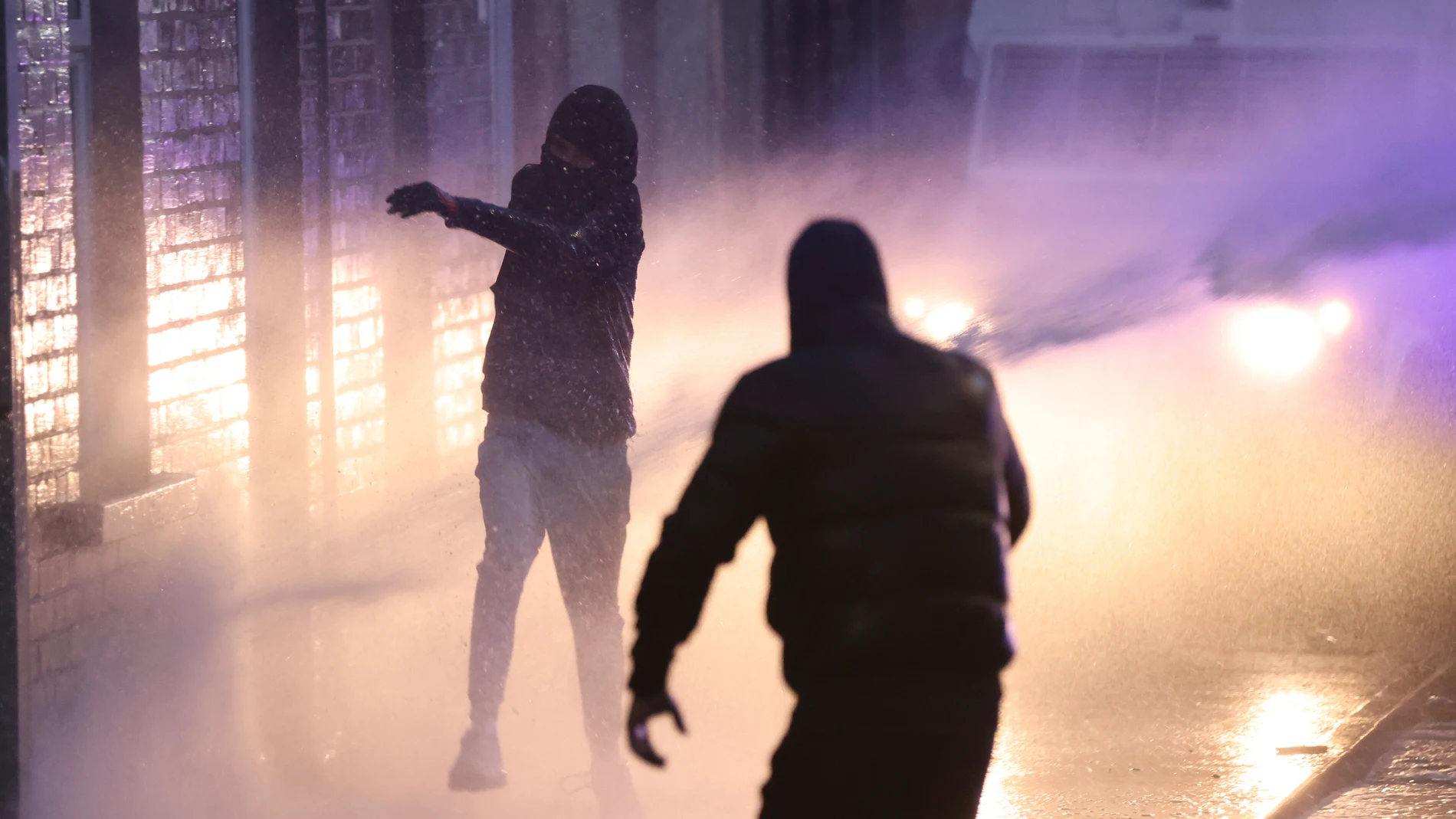 Protesters try to throw items at the police who use water canons to clear them in Ballymena, Northern Ireland, as people protest over an alleged sexual assault in the Co Antrim town, Wednesday, June 11, 2025. (AP Photo/Peter Morrison)