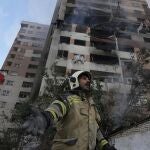 A firefighter calls out his colleagues at the scene of an explosion in a residence compound in northern Tehran, Iran, Friday, June 13, 2025. 
