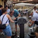 Turistas en plena ola de calor en agosto en la ciudad de Madrid intentan refrescarse en las fuentes de agua in