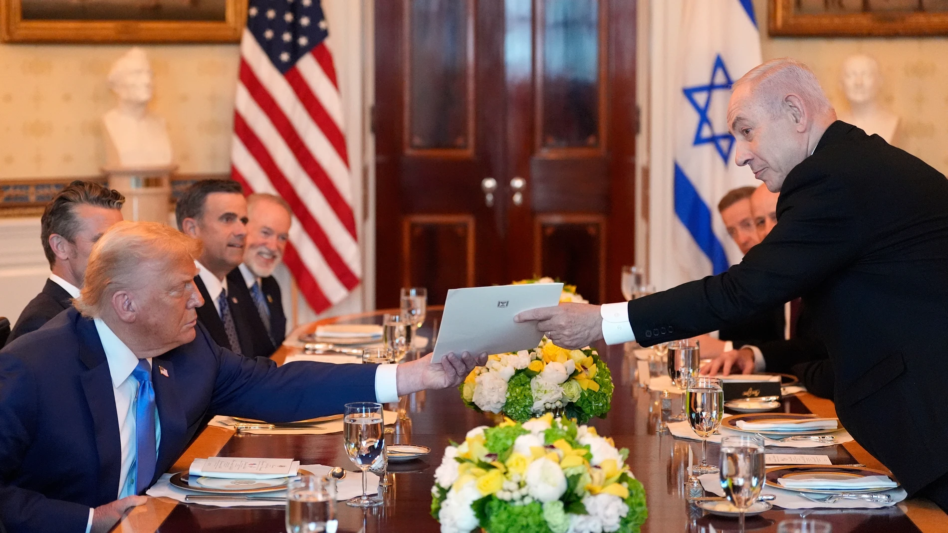 Israel's Prime Minister Benjamin Netanyahu, right, hands President Donald Trump a folder during a meeting in the Blue Room of the White House, Monday, July 7, 2025, in Washington. (AP Photo/Alex Brandon)