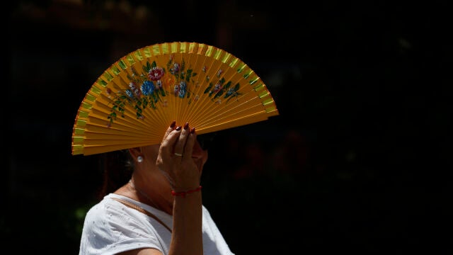 Una mujer se tapa con un abanico mientras camina por el centro histórico de Córdoba 