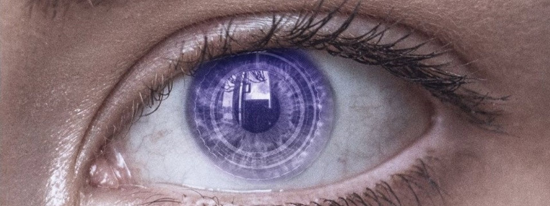 Plano Detalle de un ojo con una lentilla en la que se ven patrones geométricos de información digital.