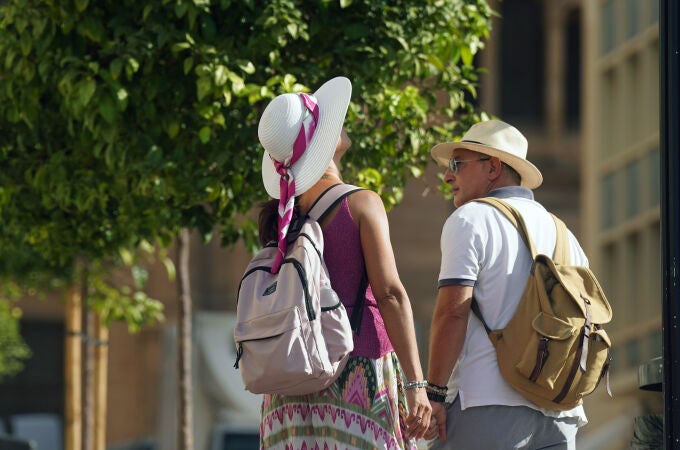 Dos personas con ropa veraniega y sombreros en Málaga