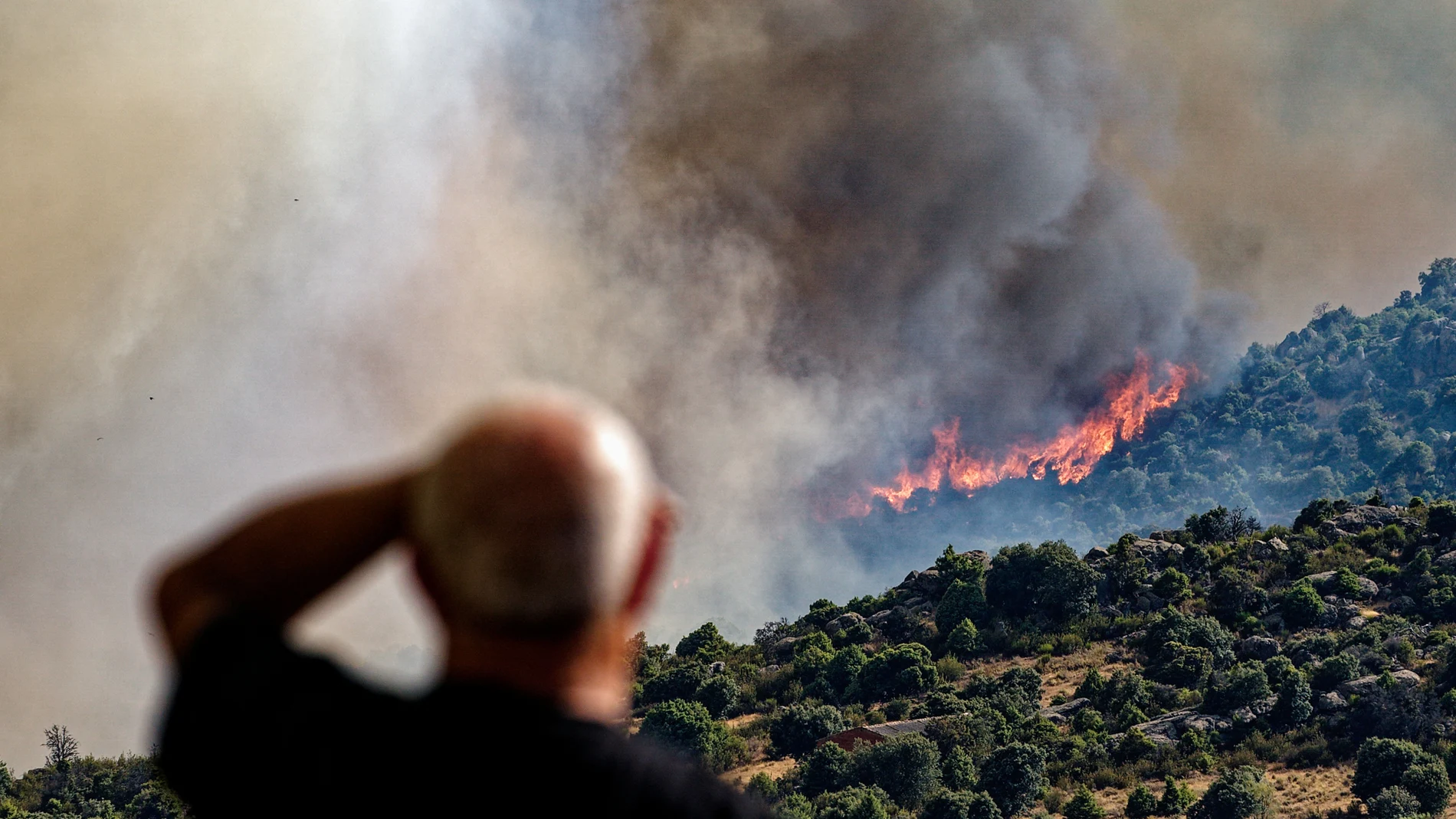 Un hombre contempla un incendio forestal declarado en el término municipal de Navaluenga (Ávila), este viernes.