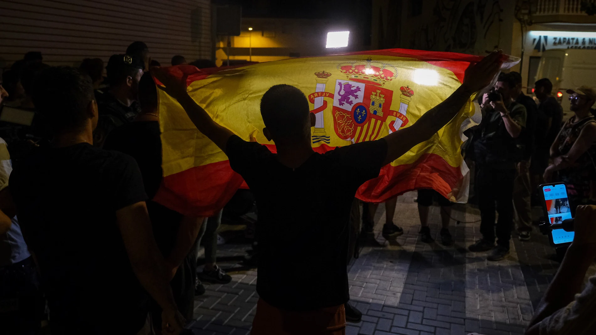 Un manifestante ondea una bandera de España mientras increpa a periodistas este martes en Torre Pacheco (Murcia). La Guardia Civil ha impedido la manifestación prevista para las 20:00 horas a las puertas del Ayuntamiento de Torre Pacheco para evitar altercados ante la presencia de grupos ultra en la población