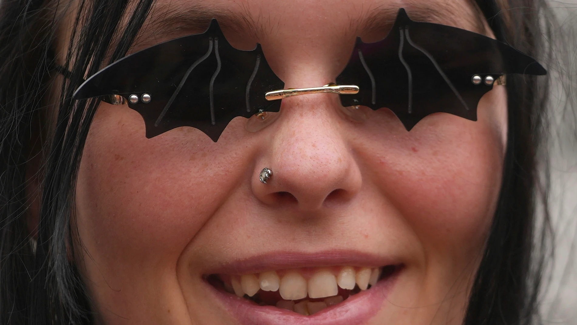 A music fan wears a sunglasses depicting bats to commemorate the death of Ozzy Osbourne at the Black Sabbath Bridge in Birmingham, Wednesday, July 23, 2025. (AP Photo/Kin Cheung)