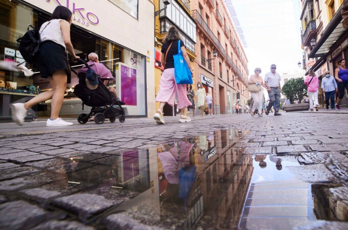 Personas reflejadas en un charco en Sevilla