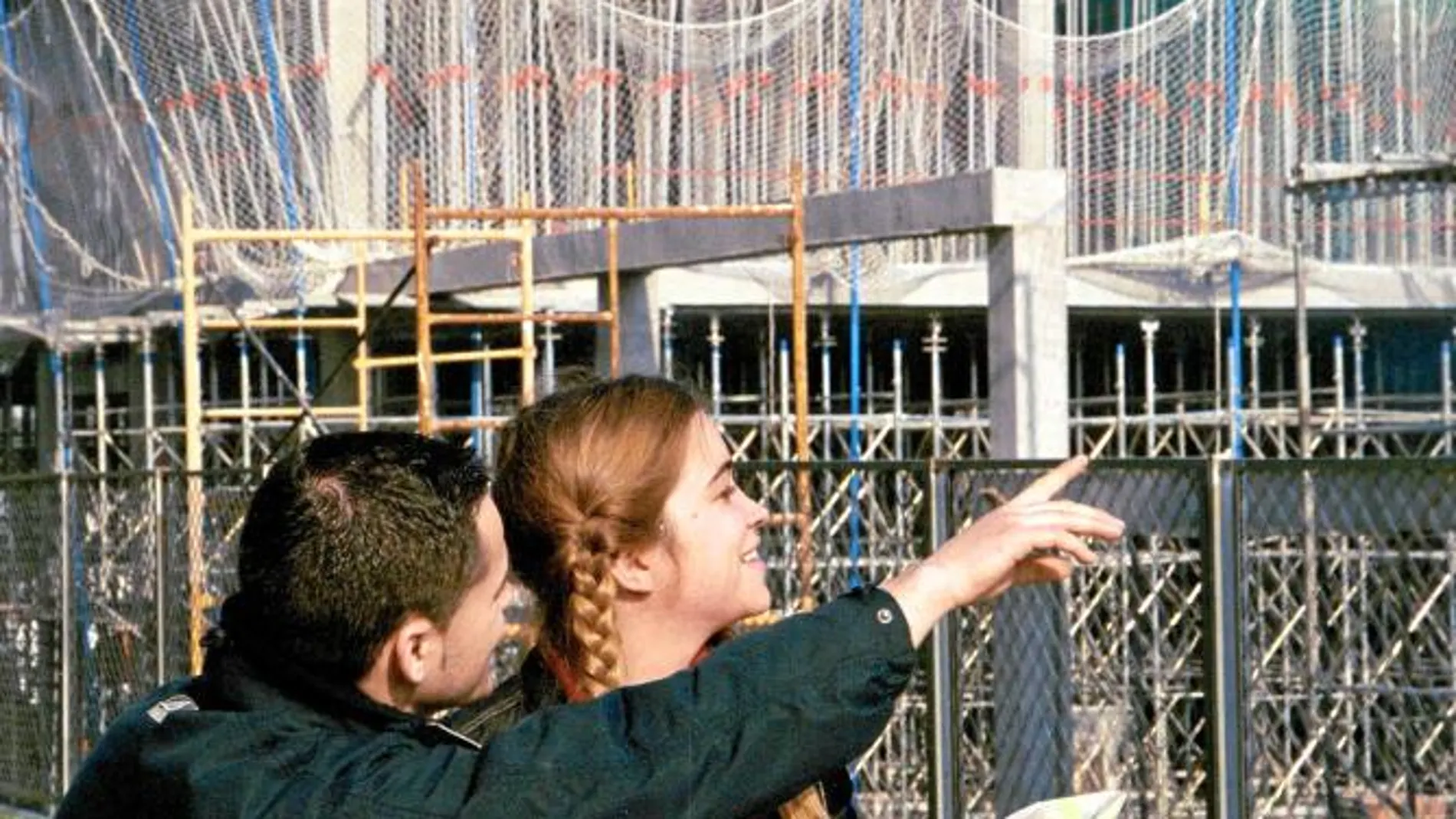 Dos jóvenes contemplan la construcción de un bloque de viviendas
