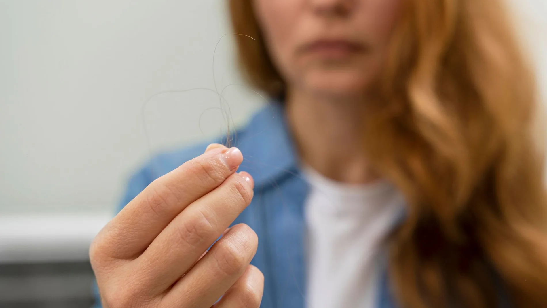 Mujer sostiene pelo y lo observa