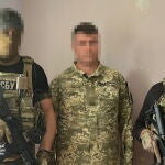 El sospechoso de traición escoltado por dos agentes del SBU 