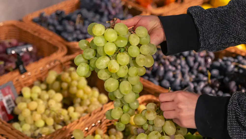 Una mujer escoge uvas en un supermercado