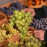 Una mujer escoge uvas en un supermercado