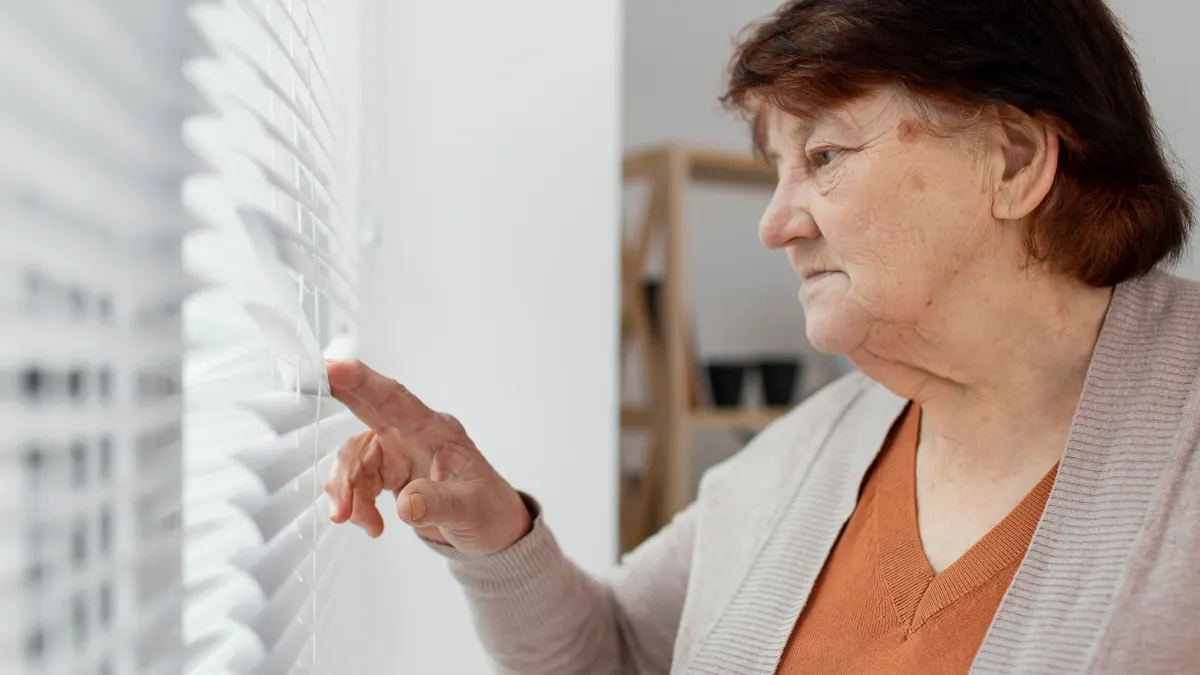 Mujer mayor regula las persianas para evitar la entrada de calor en casa