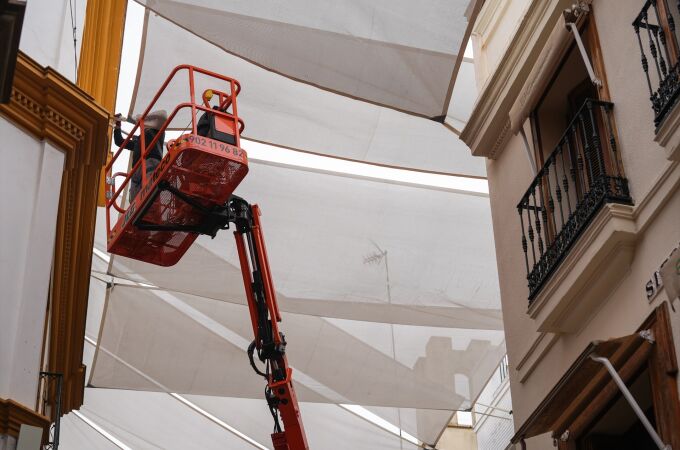 Un operario coloca toldos en la calle Sierpes