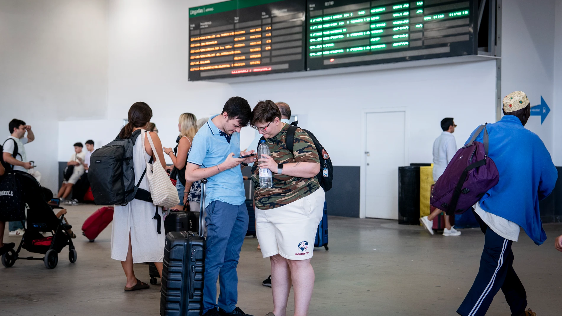 Varias personas esperan con maletas y observan los carteles de salidas, en la estación de Chamartín Clara Campoamor, a 14 de agosto de 2025, en Madrid (España). Renfe mantiene interrumpida la circulación de trenes entre Galicia y Madrid por los incendios en Ourense y continúa revisando la infraestructura para reanudar el servicio. La compañía había previsto retomar hoy los viajes si el fuego estaba controlado y programó trenes especiales para los afectados. 14 AGOSTO 2025 A. Pérez Meca / Eu...