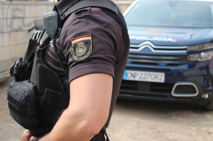 Un agente de la Policía Nacional en una imagen de archivo con un vehículo del cuerpo