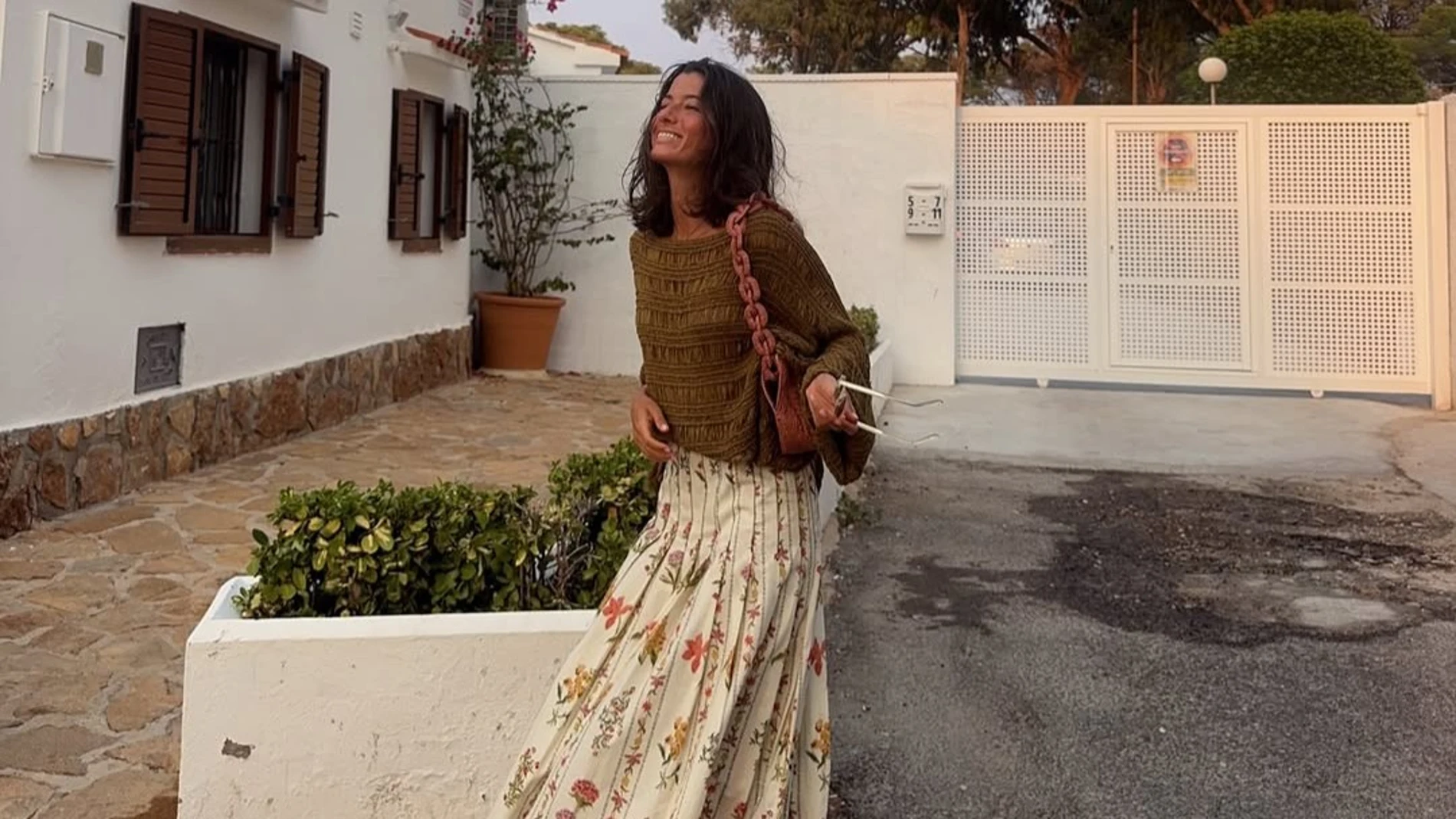 Influencer con falda midi de tablas con flores y jersey verde en un look de entretiempo de Zara