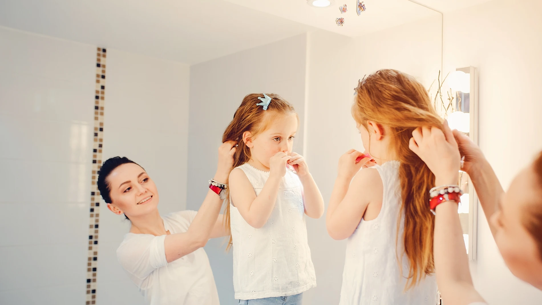 Madre preparando a su hija para el cole pinándola