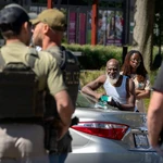 Una mujer con un niño en brazos grita a los agentes federales que se encuentran en un puesto de control operado por el Departamento de Policía Metropolitana y otras agencias federales, incluyendo agentes del Servicio de Inmigración y Control de Aduanas (ICE) y la Oficina de Investigaciones de Seguridad Nacional (HSI), en Washington
