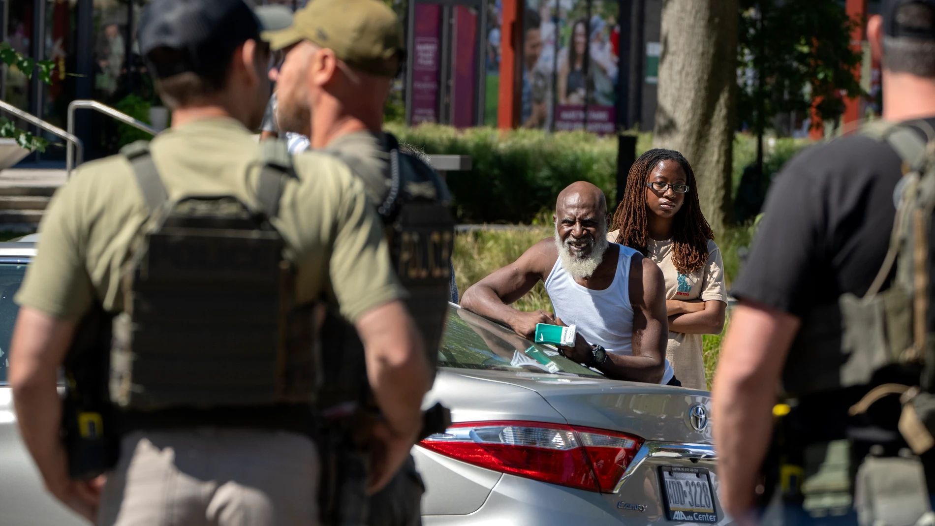 Neighbors watch as federal officers stand at a checkpoint operated by the Metropolitan Police Department and federal agencies, including officers from Immigration and Customs Enforcement (ICE) and Homeland Security Investigations (HSI), on Georgia Avenue in the northern part of Washington, Saturday, Aug. 30, 2025. (AP Photo/Mark Schiefelbein)
