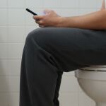 Una persona usando el móvil en el WC