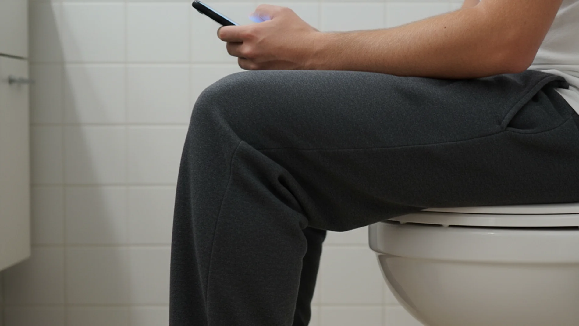 Una persona usando el móvil en el WC
