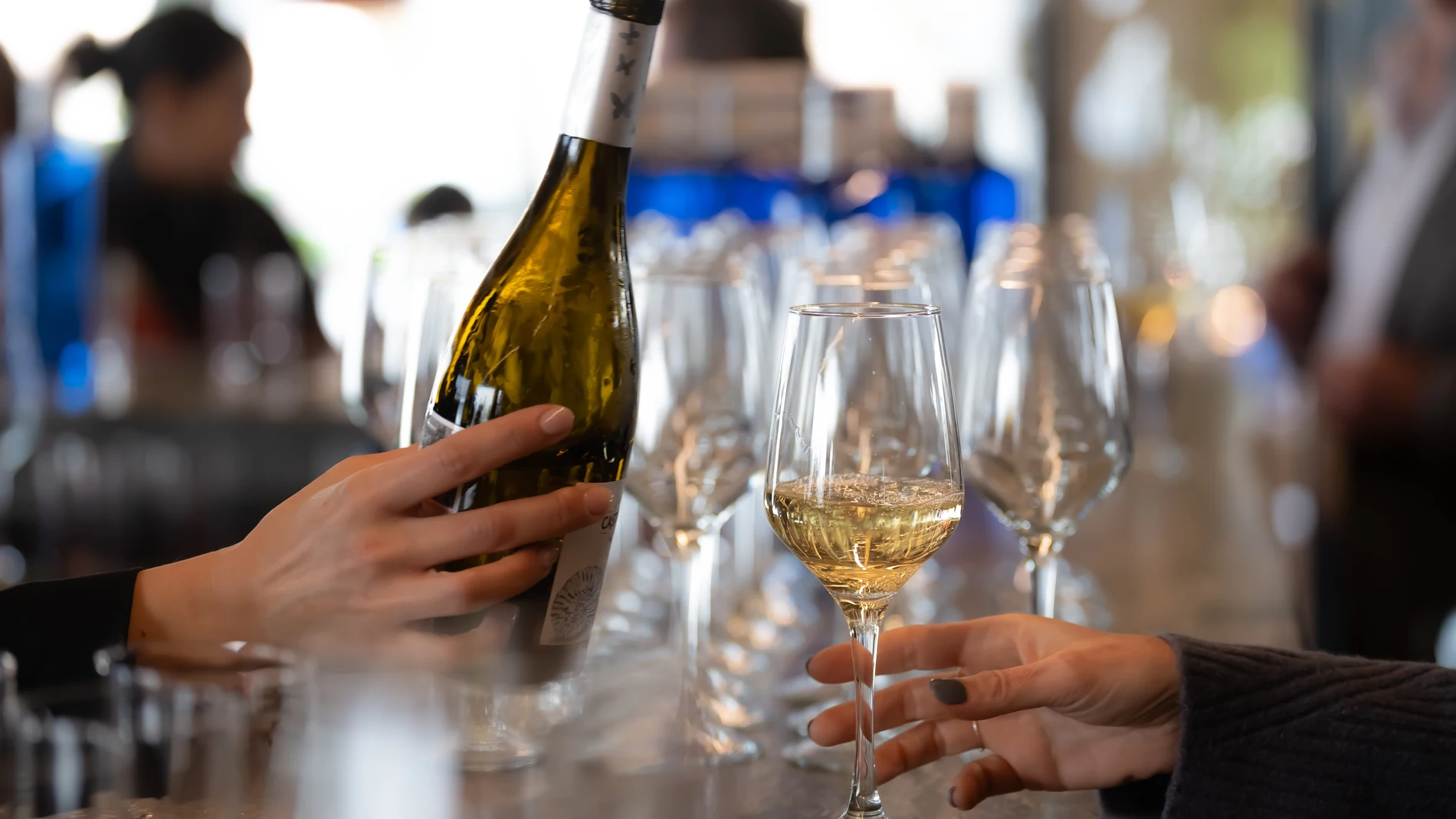 Un camarero sirve vino blanco en un establecimiento de hostelería