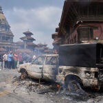 Personas observan un vehículo policial incendiado durante las protestas contra la prohibición de las redes sociales y la corrupción en Katmandú, Nepal