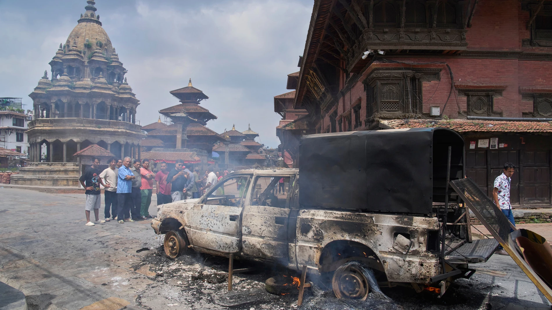Personas observan un vehículo policial incendiado durante las protestas contra la prohibición de las redes sociales y la corrupción en Katmandú, Nepal