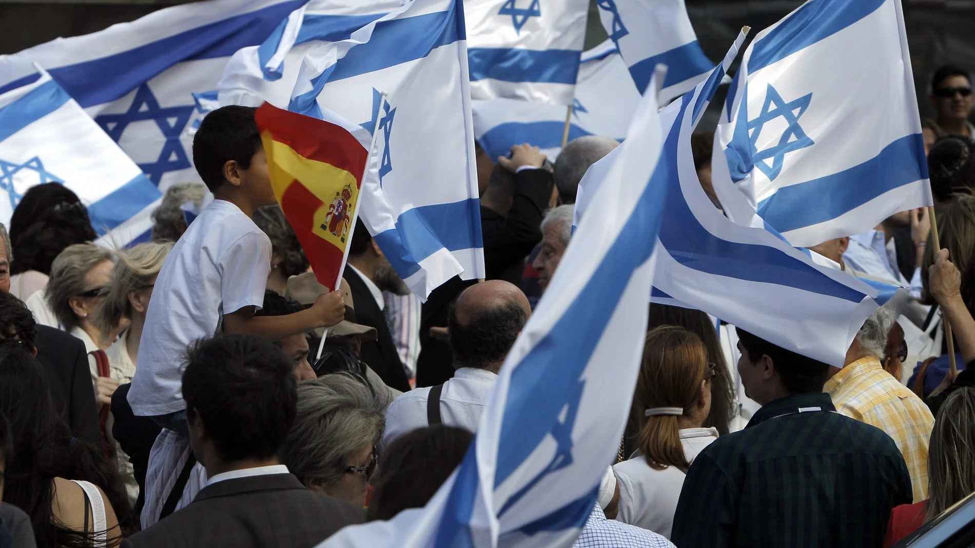 Un niño enarbola una bandera de España entre enseñas de Israel