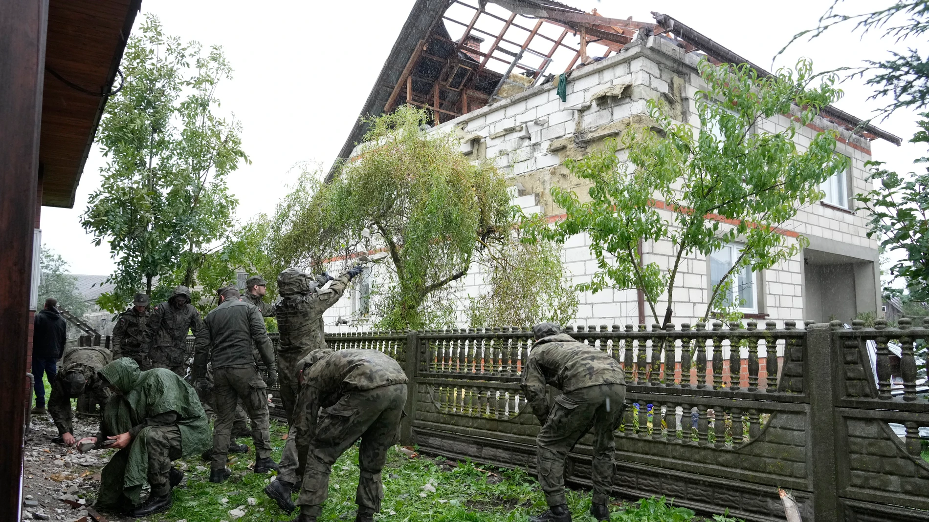 Territorial defense officers clean up debris from the destroyed roof of a house, after Russian drones violated Polish airspace during an attack on Ukraine, in Wyryki near Lublin, Poland, Thursday, Sept. 11, 2025. (AP Photo/Czarek Sokolowski)