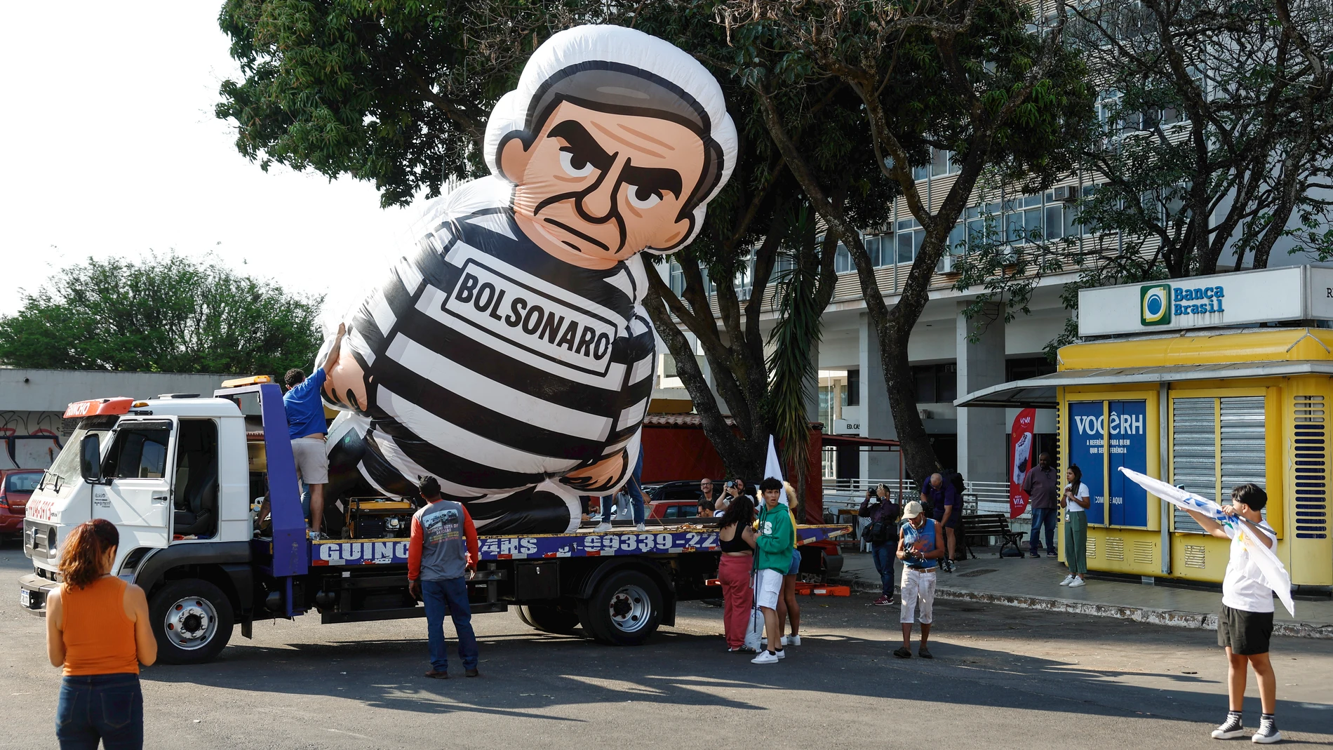 AME8954. BRASILIA (BRASIL), 12/09/2025.- Personas caminan junto a un muñeco alusivo al expresidente de Brasil Jair Bolsonaro durante un desfile este viernes, en Brasilia (Brasil). Un grupo de estudiantes brasileños desfiló este viernes por Brasilia con un muñeco inflable de Bolsonaro vestido de recluso, un día después de ser condenado a 27 años y tres meses de prisión por golpismo. EFE/ Antonio Lacerda