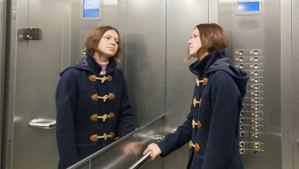 Foto de una chica mirándose en el espejo del ascensor
