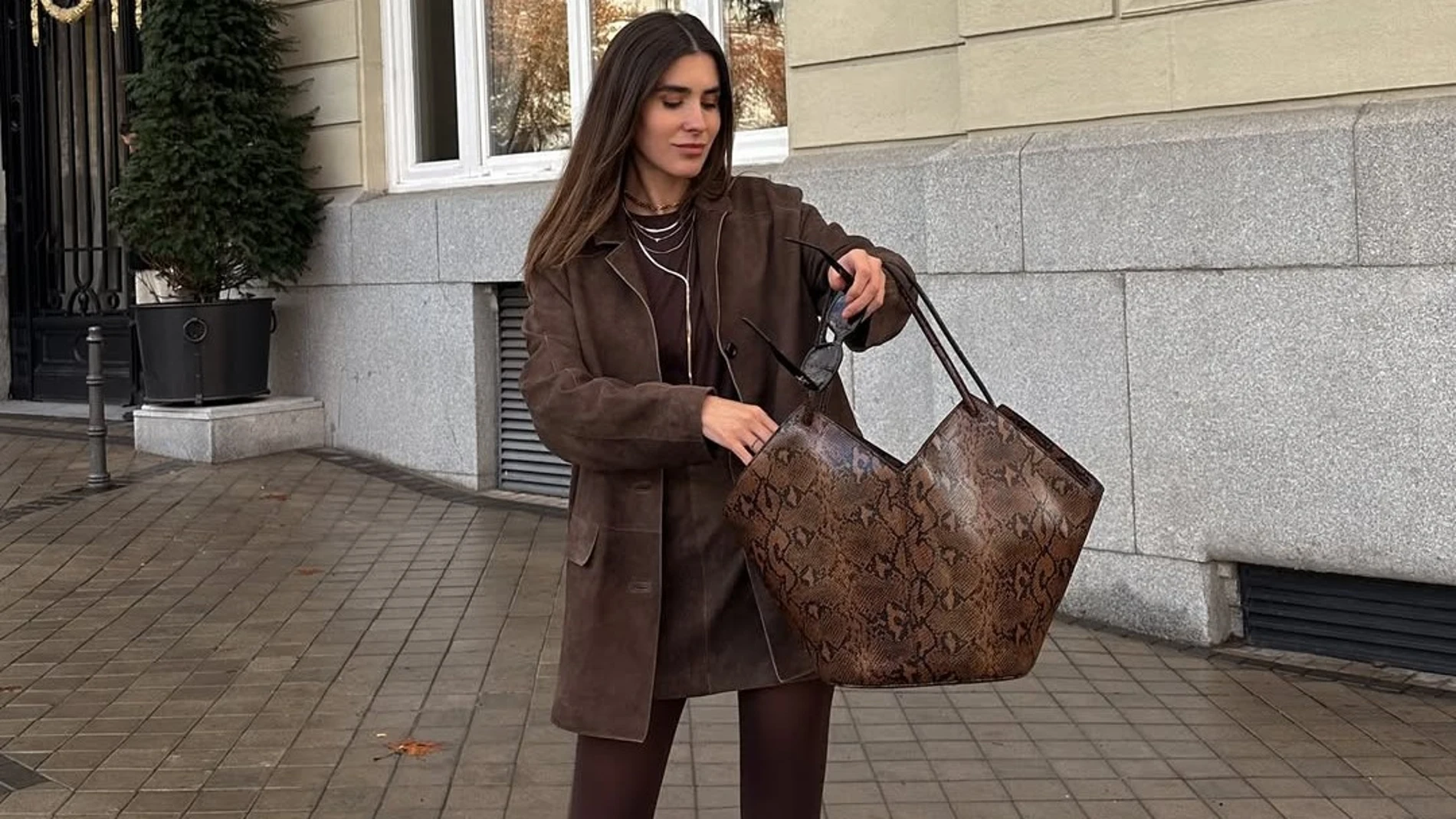 Influencer con total look en tonos marrón chocolate en la calle, con blazer, minifalda y bolso XL de estampado serpiente.