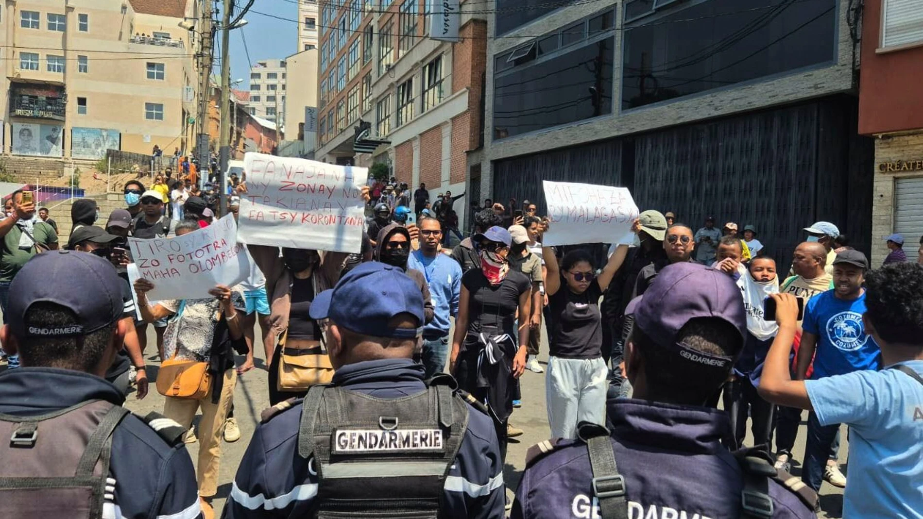 Demonstrators hold up placards reading "water and electricity are basic human rights," "Malagasy people, wake up," "Let's not remain in the dark with our yellow cans" in Antananarivo, Madagascar, Thursday, Sept. 25, 2025. (AP Photo/Sarah Tetaud)