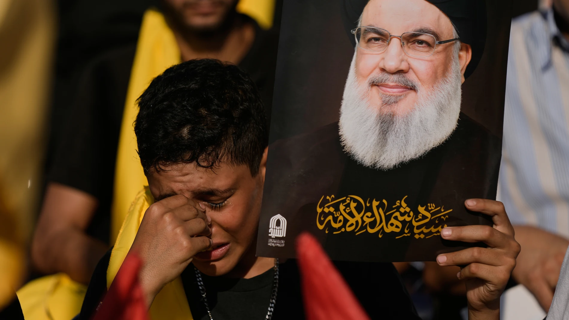 A Hezbollah supporter weeps as he hold an image of Hezbollah leader Sayyed Hassan Nasrallah, who was killed in Israeli airstrikes, during a ceremony at Nasrallah's grave in Beirut, Lebanon, Saturday, Sept. 27, 2025, marking the first anniversary of his assassination. (AP Photo/Bilal Hussein)