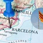 Imagen del mapa de España con una chincheta sobre Barcelona junto a una bandera de Cataluña