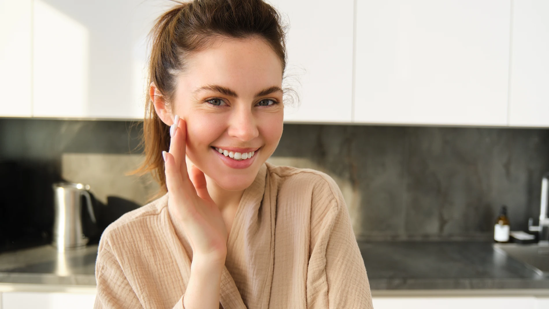 Mujer sonriente en casa tras completar una rutina facial exprés de 5 minutos con piel luminosa.