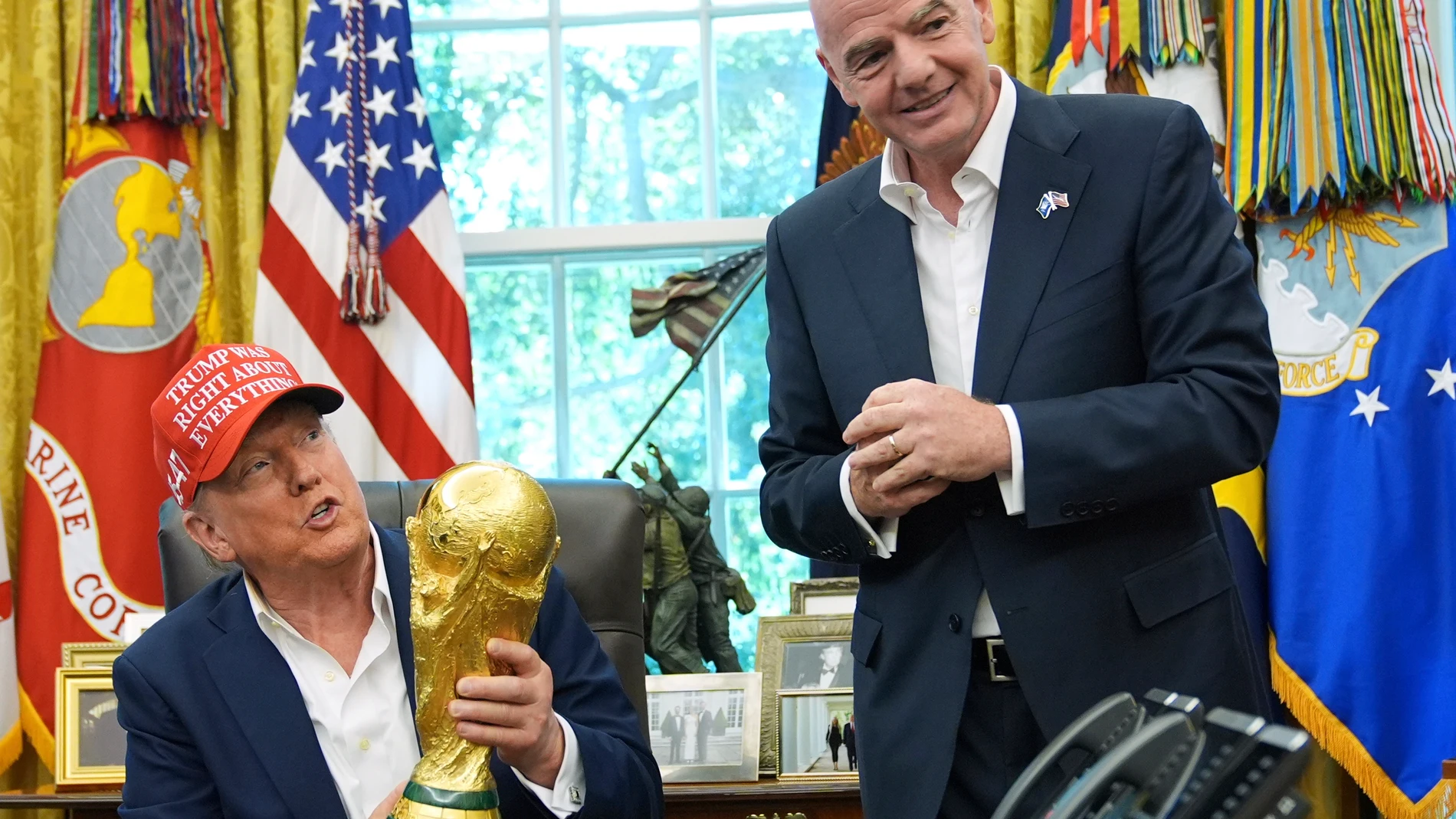 FILE - President Donald Trump holds the FIFA World Cup Winners Trophy as FIFA President Gianni Infantino looks on during an announcement in the Oval Office of the White House, Aug. 22, 2025, in Washington. (AP Photo/Jacquelyn Martin, File)