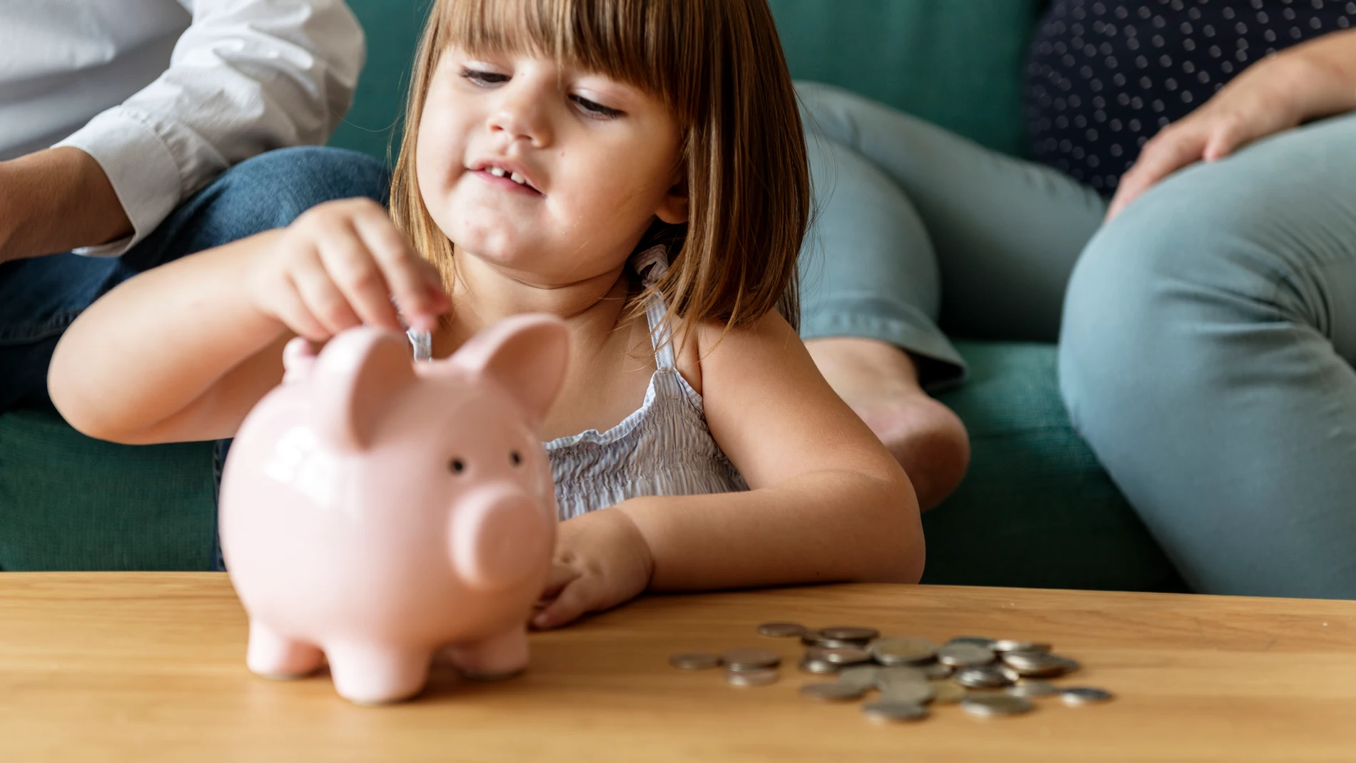 Niña usa hucha para guardar dinero en monedas, concepto de educación financiera