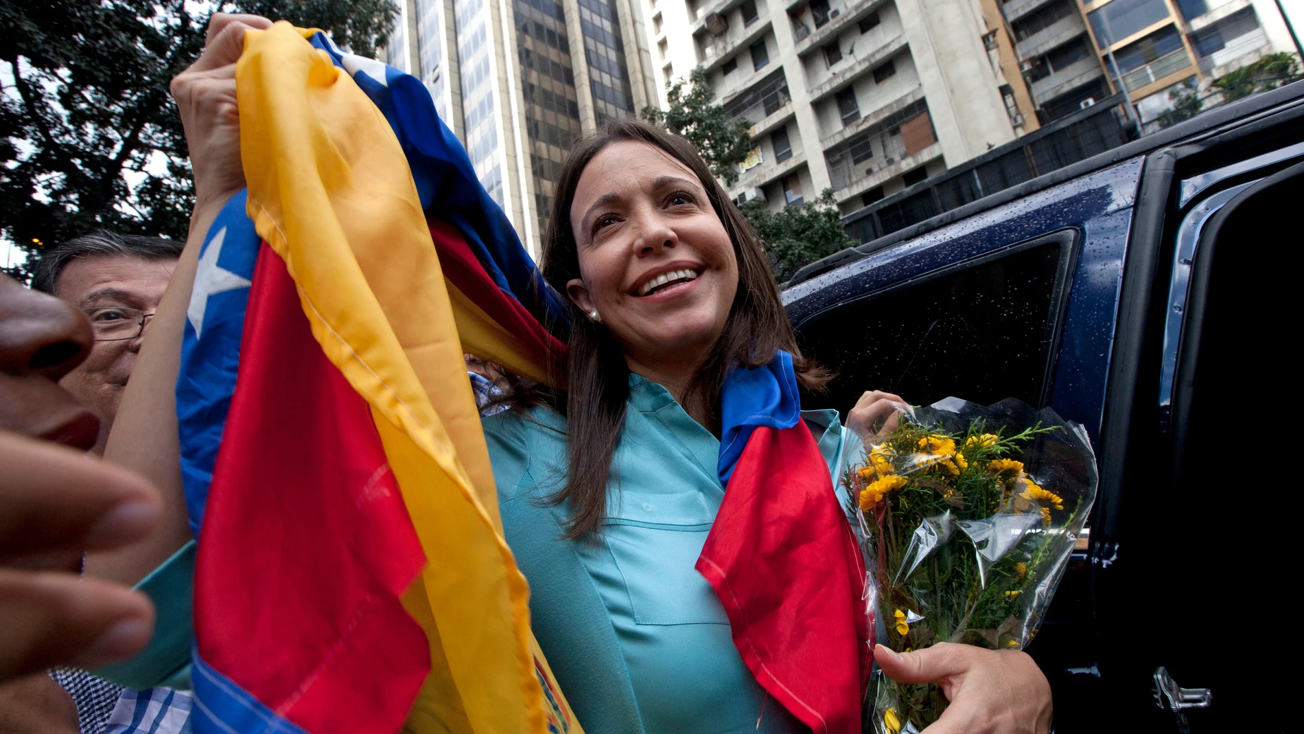FILE - Former Congresswoman and opposition leader Maria Corina Machado holds up the Venezuelan flag outside of the Attorney General Office in Caracas, Venezuela, Wednesday, Dec. 3, 2014. (AP Photo/Ariana Cubillos, File)