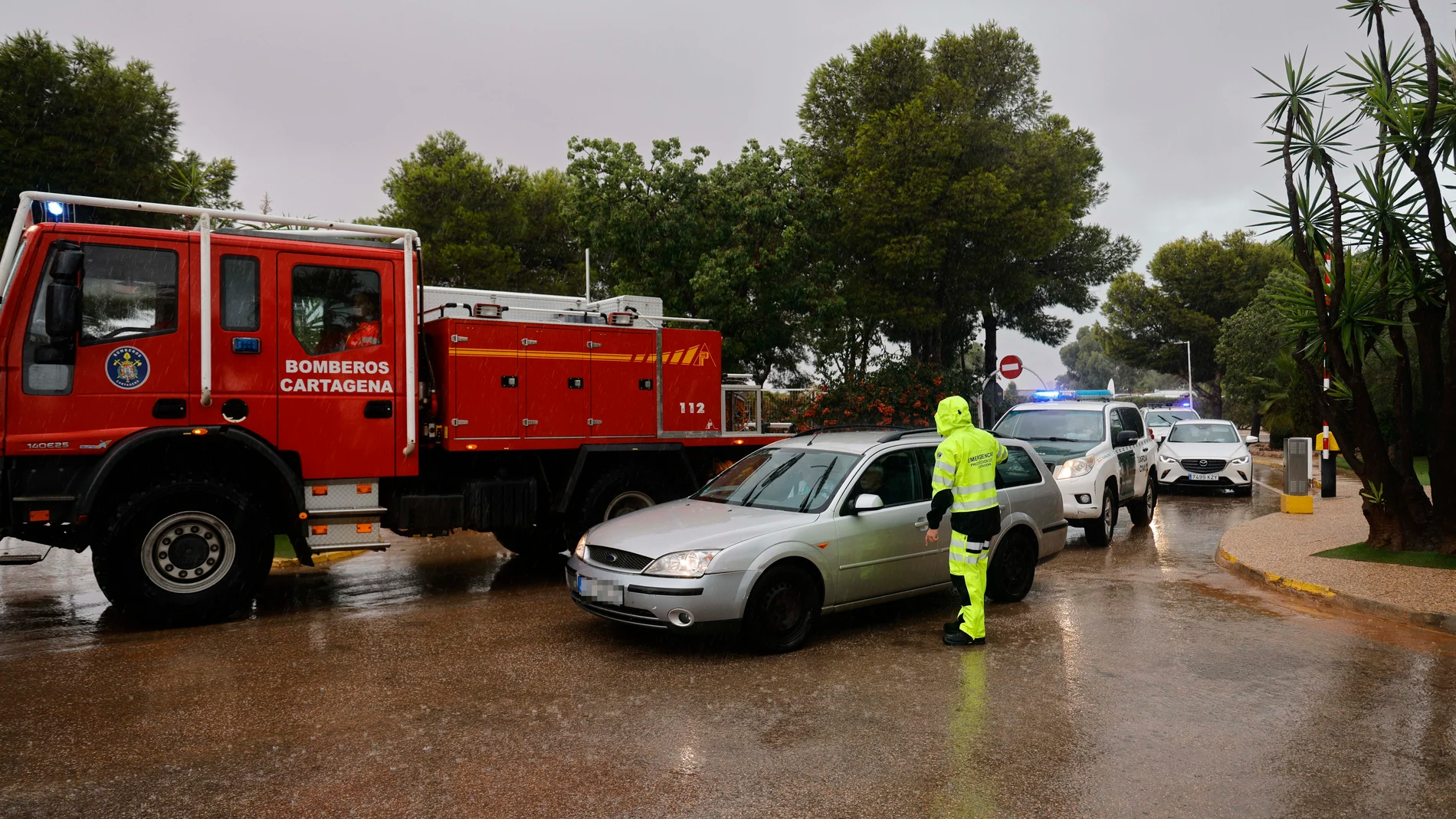 Un camión de bomberos y Protección Civil de Cartagena regula el tráfico por las fuertes lluvias, a 10 de octubre de 2025, en Cartagena, Región de Murcia (España). El Ayuntamiento de Cartagena ha ordenado el desalojo de las personas que hay en Villas Caravaning, Bahía Bella y La Algameca, al producirse acumulaciones de agua por lluvias y escorrentías en estás áreas del municipio. También, se está produciendo el desalojo de los trabajadores de Navantia, al encontrarse la factoría junta a la ram...