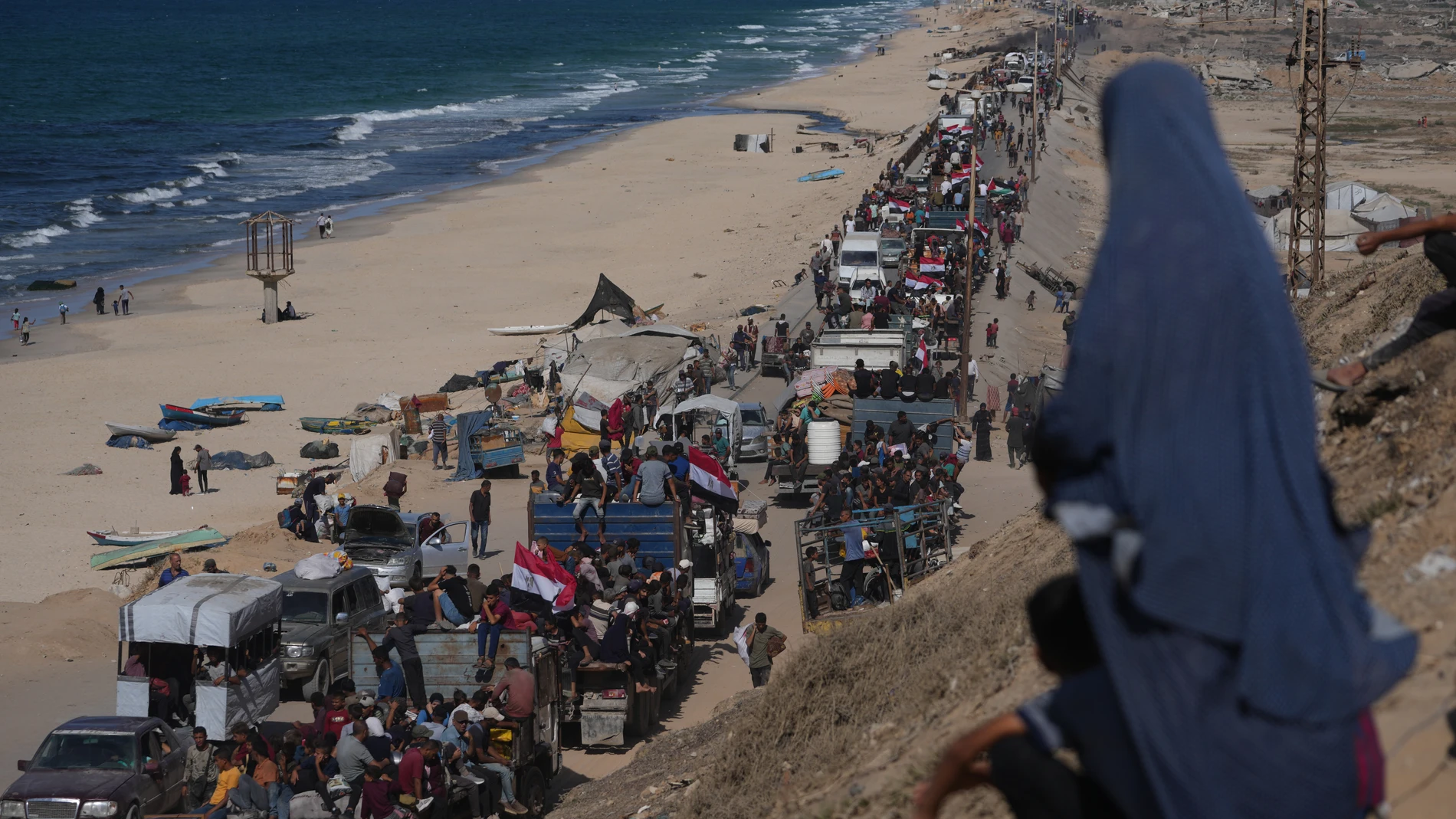 FILE - Displaced Palestinians ride on trucks loaded with belongings and wave Egyptian and Palestinian flags as they travel along the coastal road near Wadi Gaza in the central Gaza Strip, moving toward Gaza city, Saturday, Oct. 11, 2025, after Israel and Hamas agreed to a pause in their war and the release of the remaining hostages. (AP Photo/Jehad Alshrafi, File)
