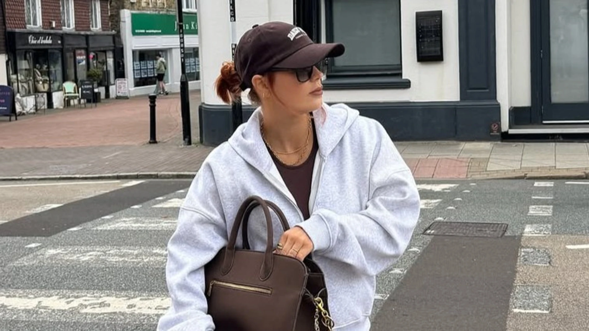 Modelo con sudadera gris con capucha y cremallera de Bershka, una prenda versátil que puede llevarse sola o como parte del chándal.