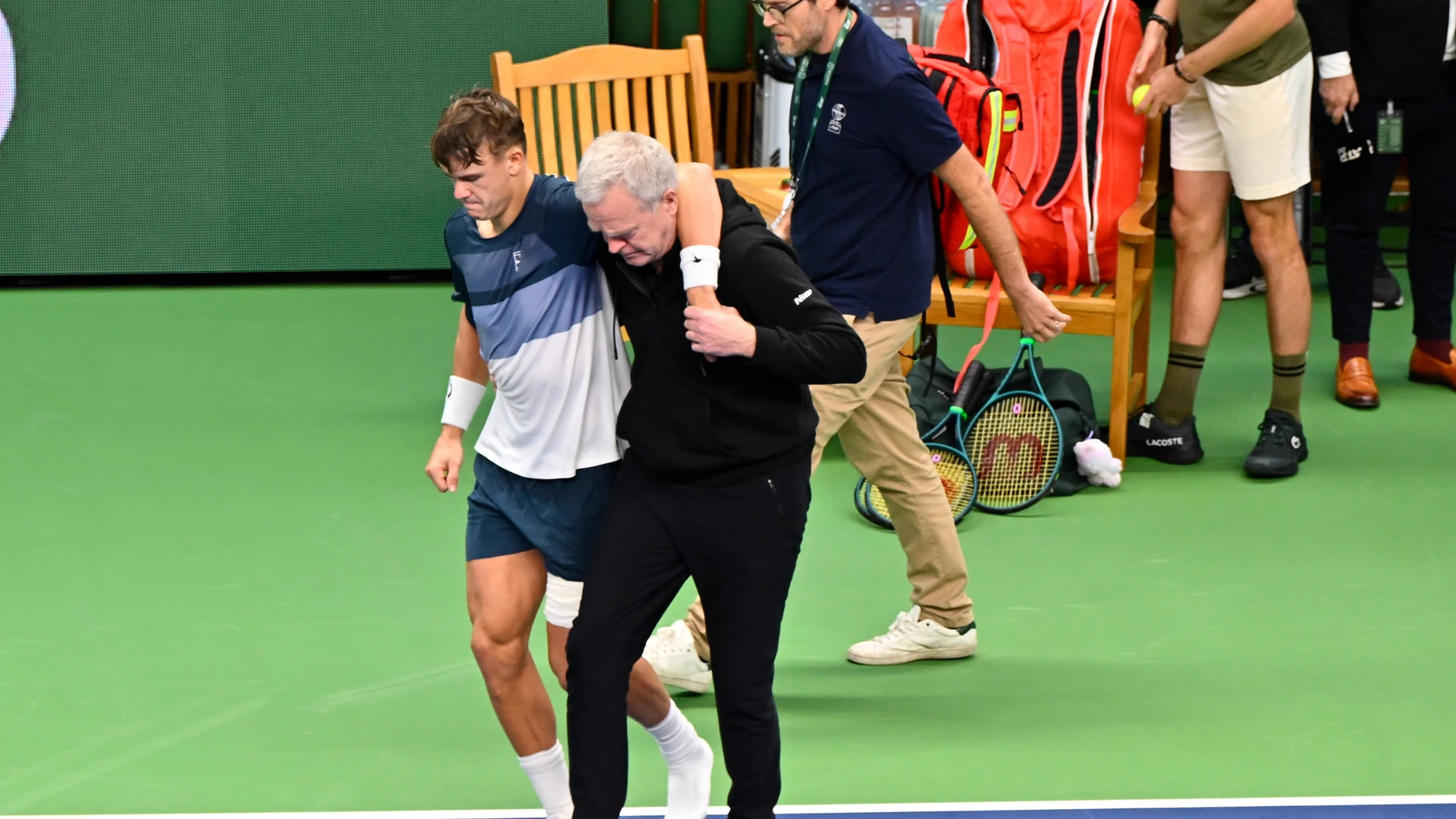 Denmark's Holger Rune is helped after injuring his foot during the men's singles semifinal tennis match against France's Ugo Humbert at the BNP Paribas Nordic Open tennis tournament in Stockholm, Sweden, Saturday, Oct. 18, 2025. (Anders Wiklund/TT via AP)