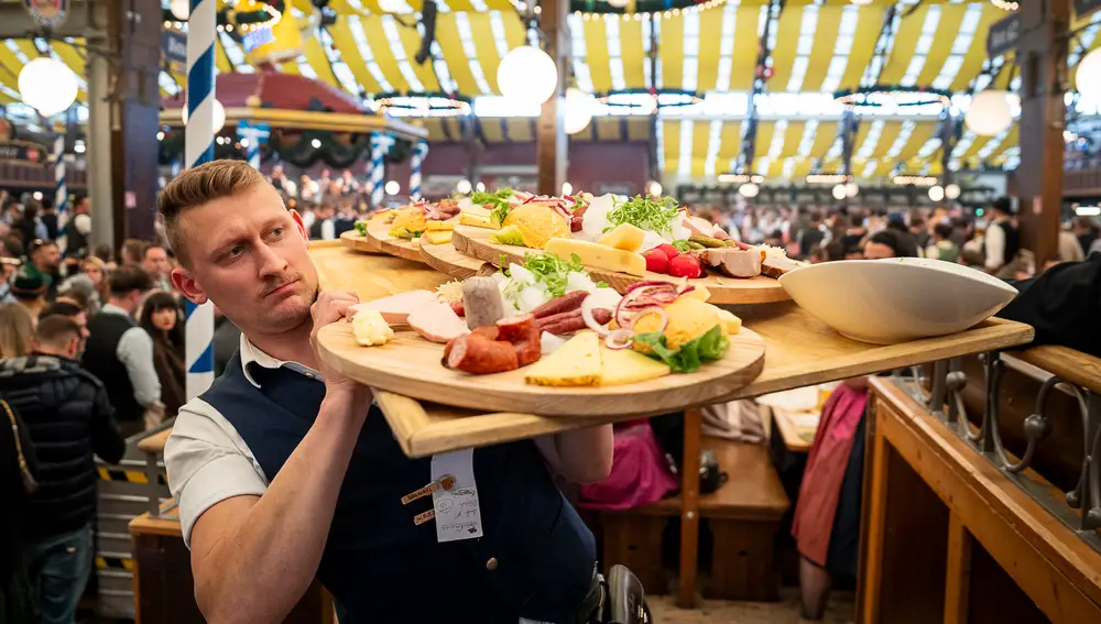 Un camarero lleva una gran bandeja de comida en en pabellón de Paulaner del Oktoberfest